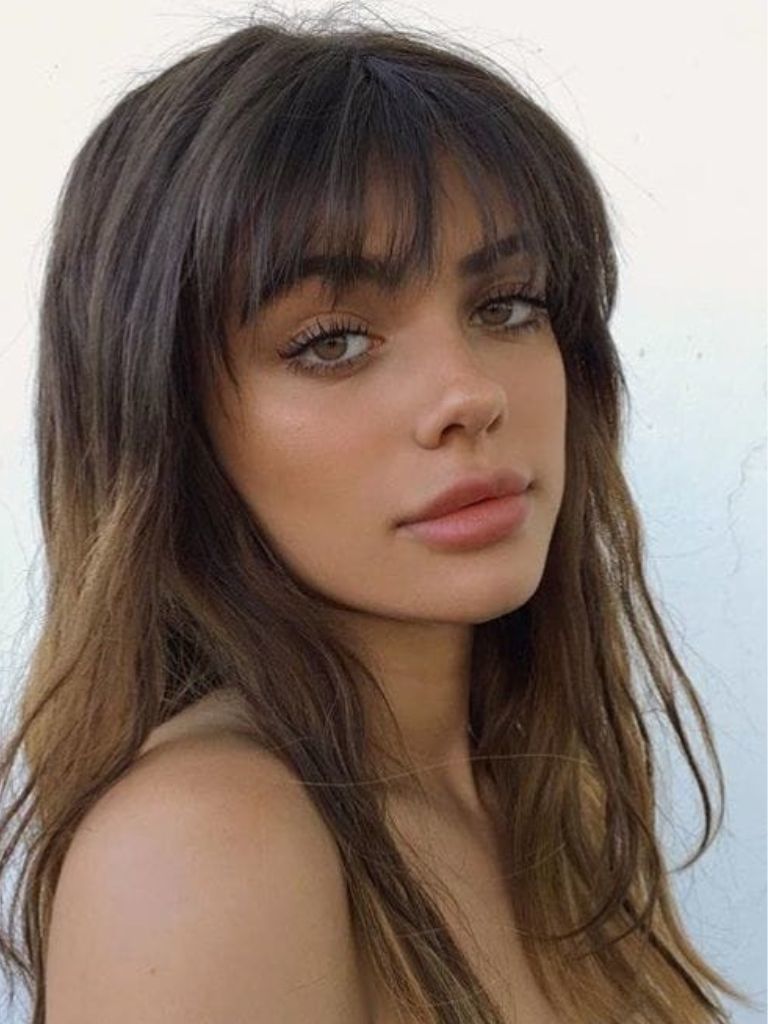 close up shot of woman with wispy bangs, with ombre hair, posing outside