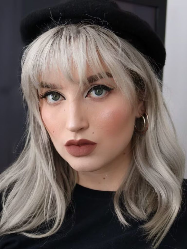 Woman with white blonde hair with wispy bangs and beret