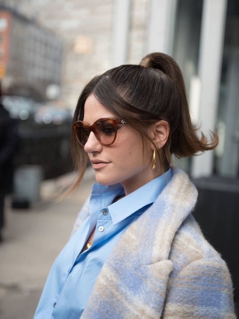 Brunette woman with her hair in a ponytail with 90s style split bangs
