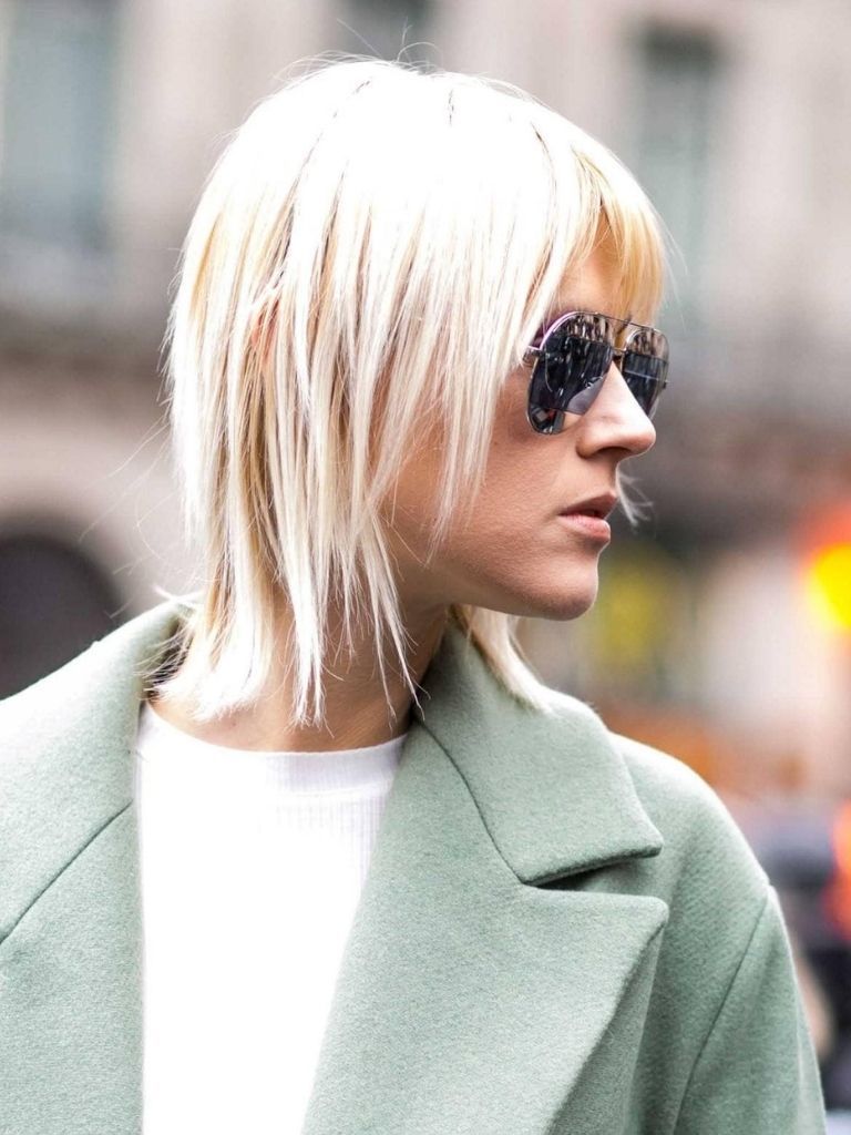 Blonde woman with short hair and wipsy fringe hair cut looking to her right