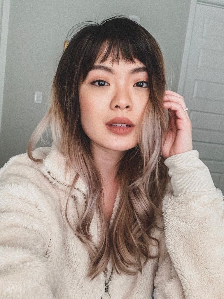 Woman with long dark to ash blonde ombre with choppy bangs
