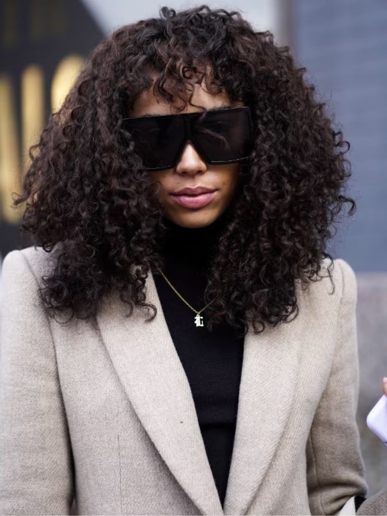Woman with dark brown curly natural hair with bangs