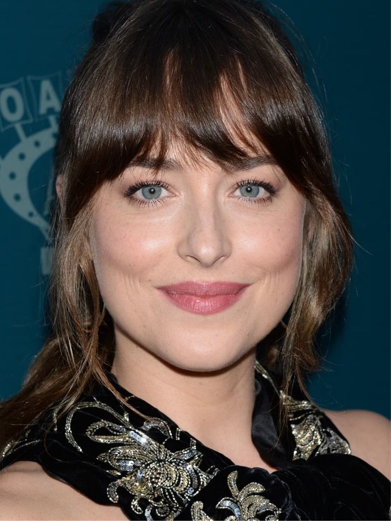 Dakota Johsnon with brunette wavy hair in a ponytail with long bangs
