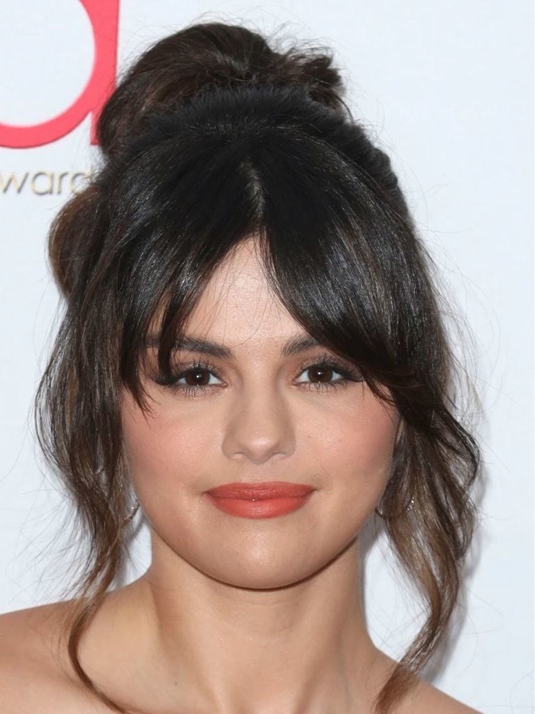 Selena Gomez with brunette hair in an updo with curly split bangs