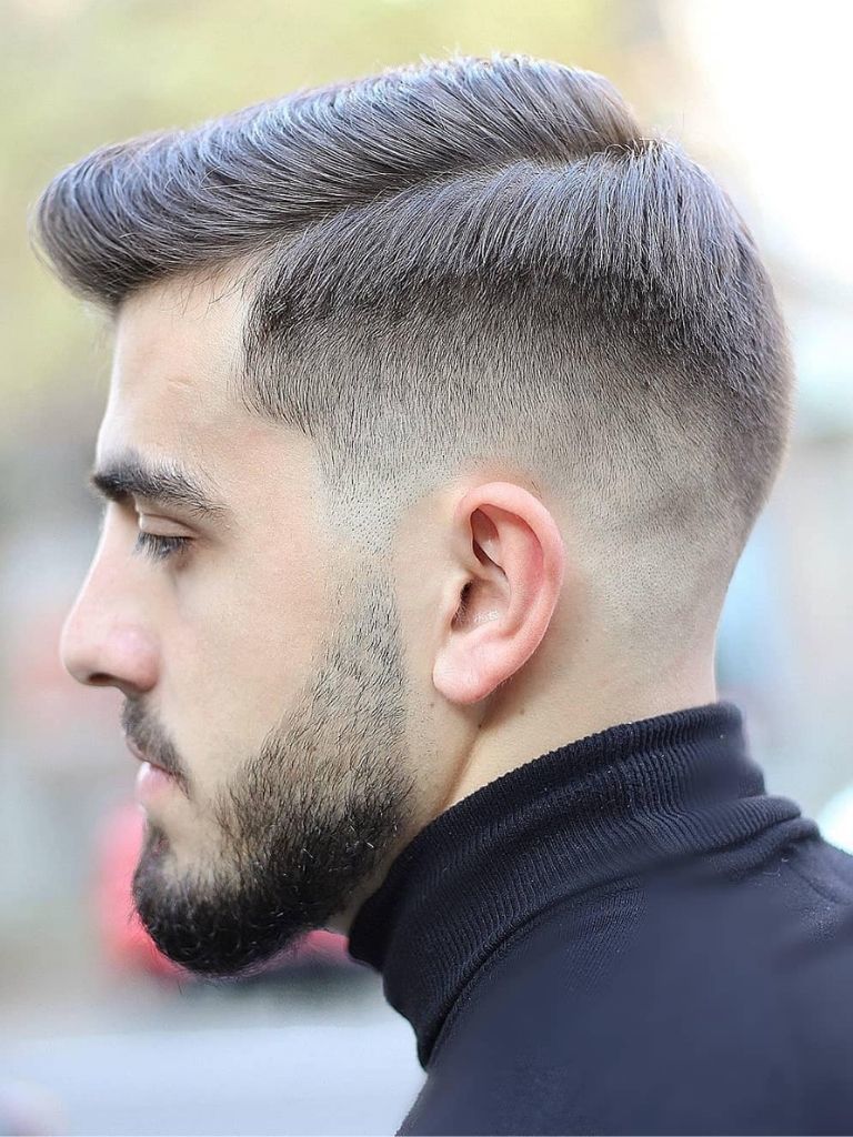Man with brown hair in a comb over style with a low fade