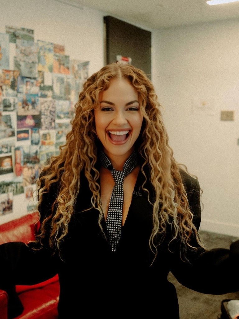Rita Ora with honey blonde curly hair