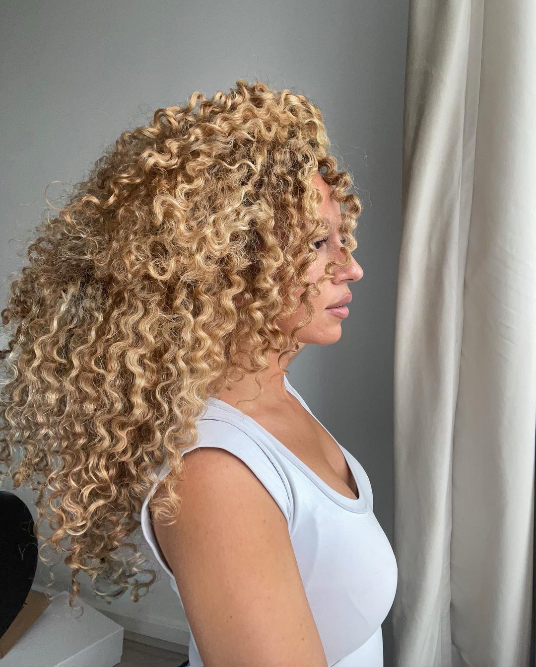 Woman in a white t-shirt with golden blonde curls