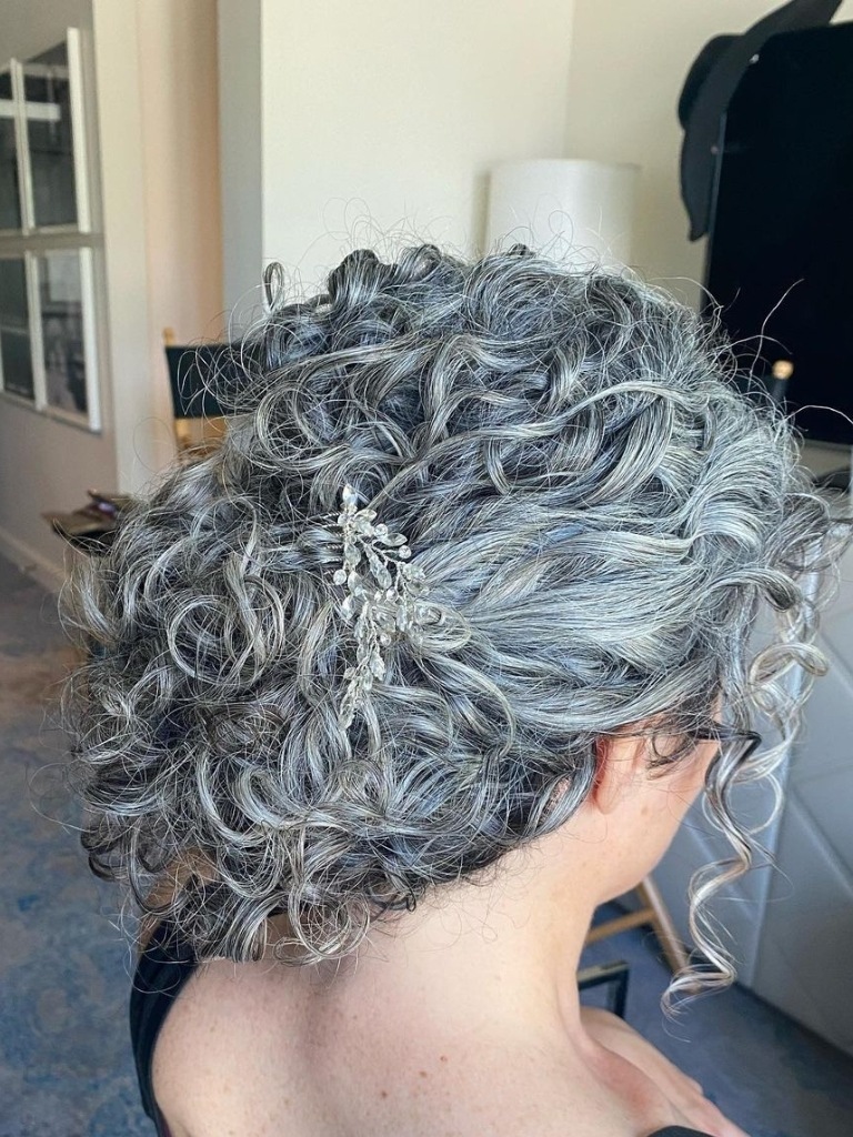 Woman with silver curly hair in a bun