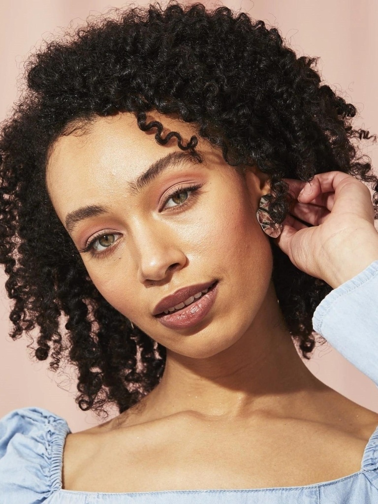 Woman with 3C hair type against a coral background