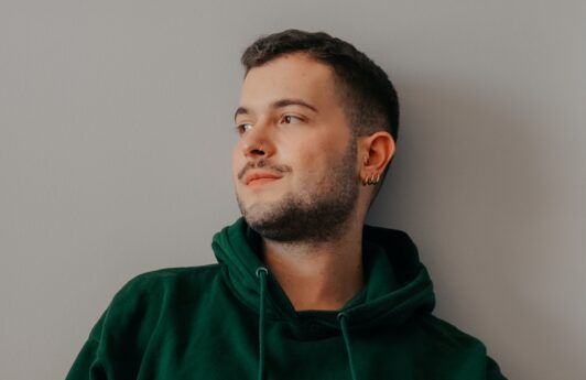 Man with short hair in a green hoodie