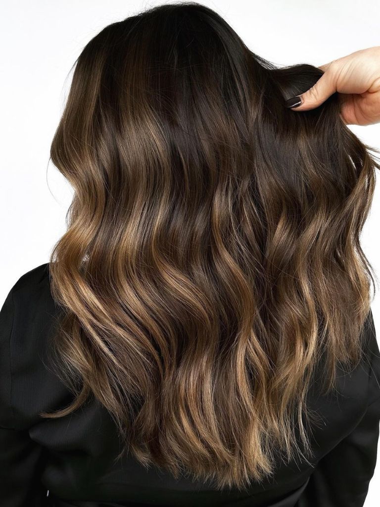 Woman in hair salon with dark brown low-lighted hair.