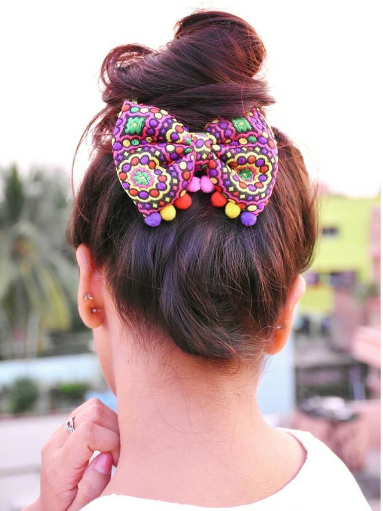 Woman with high messy bun with colourful boho-style bun underneath.