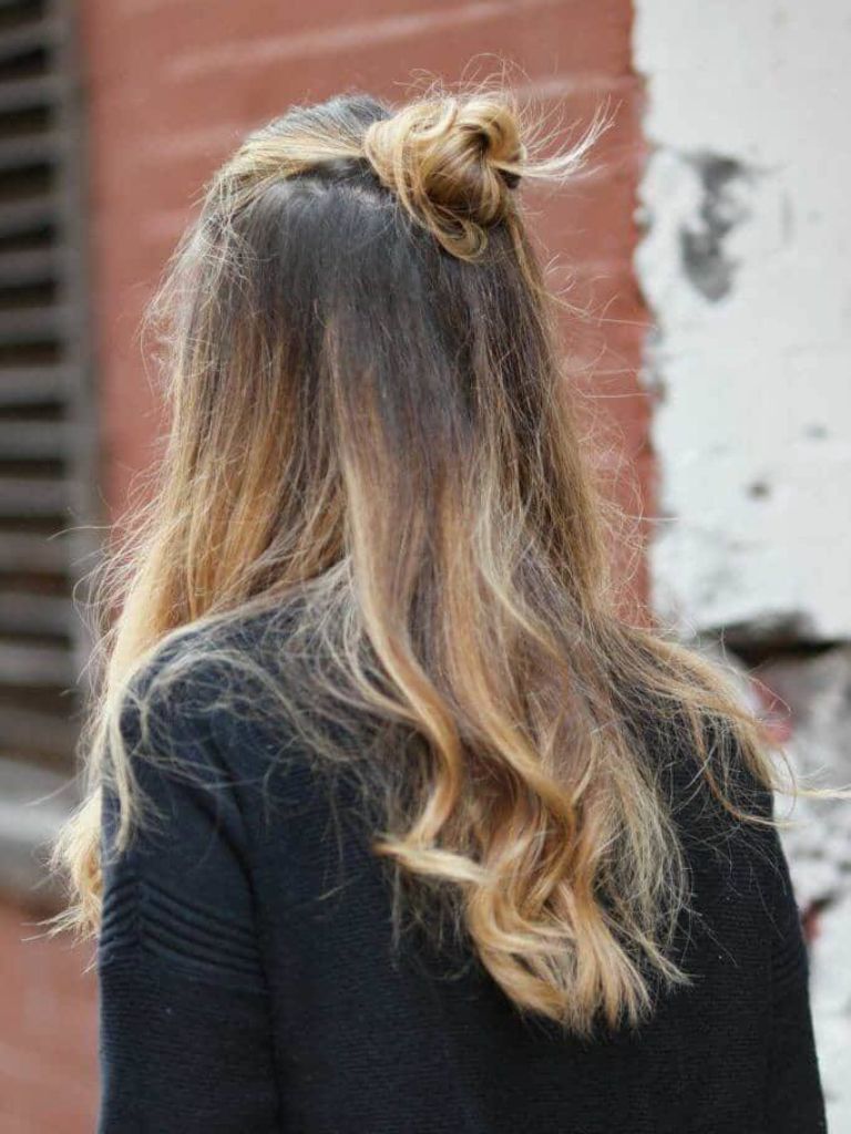 Woman with long ombre hair wearing a half-up bun.