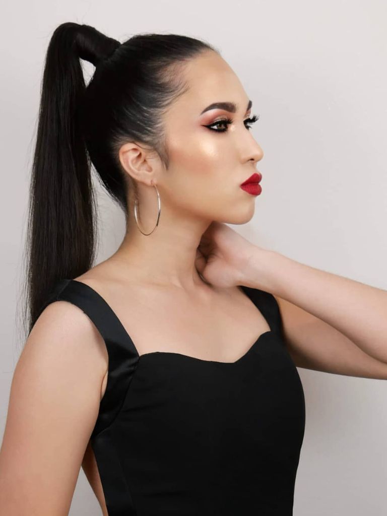 Woman with shiny black long high ponytail, hoop earrings and glam makeup.