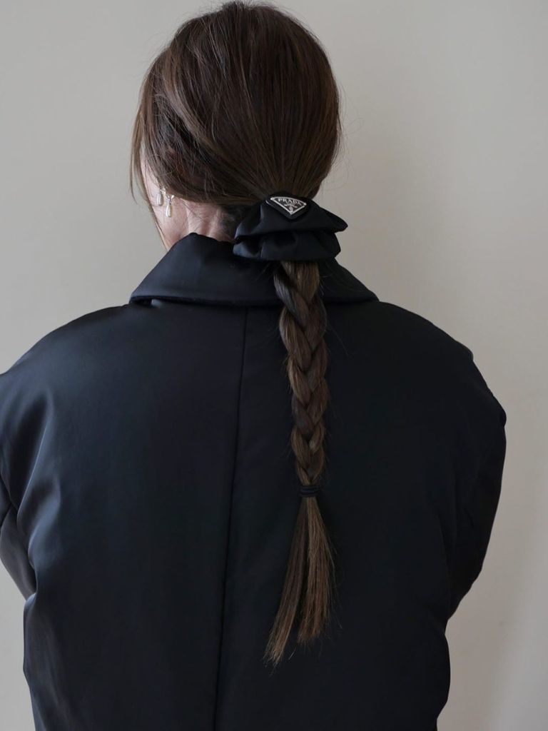 Woman with dark brown low braided plait wearing all black.
