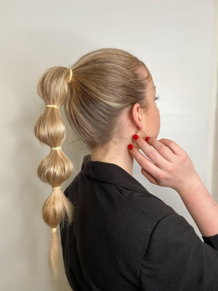 Woman with long blonde bubble braid ponytail.