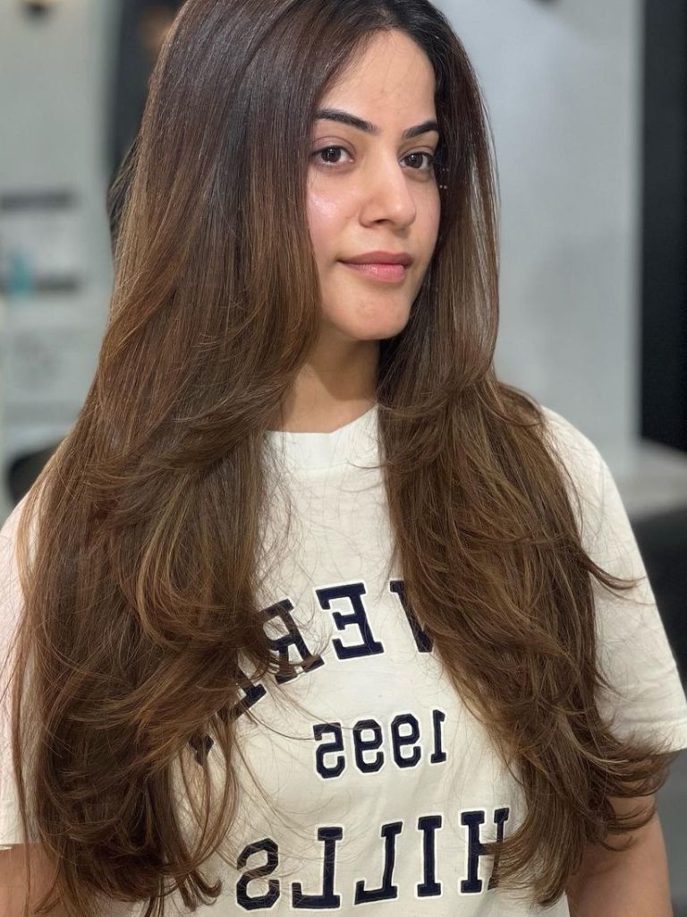 Woman with long medium brown hair with layers and curled ends.