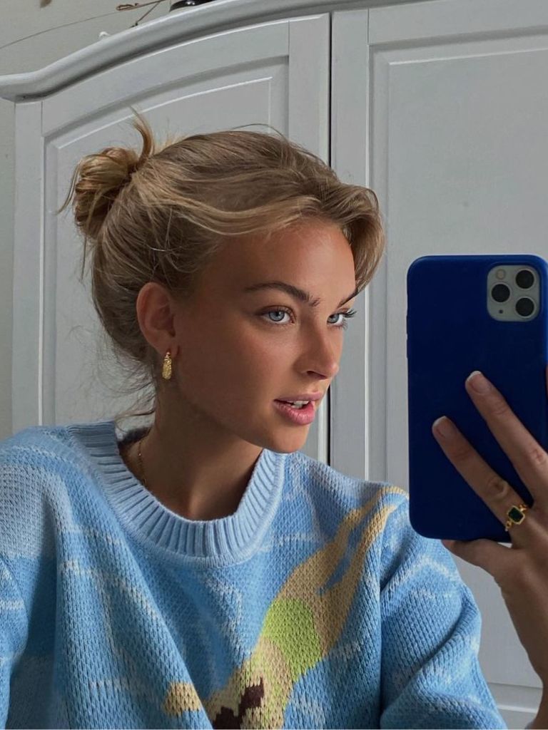 Woman with blonde bun with wispy ends.