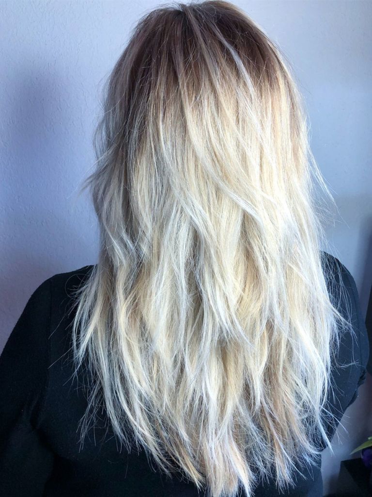Hairstyles for long thin hair: Woman with platinum blonde hair with choppy layers from the back.