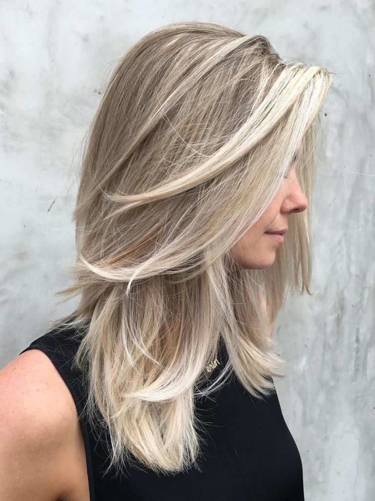 Woman with bright blonde hair and sliced layers wearing a black top.