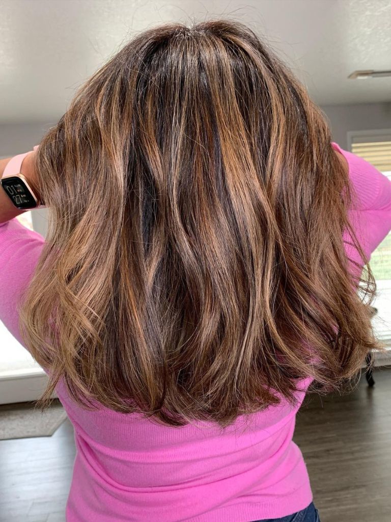 Woman with medium brown highlighted hair and blunt layers.