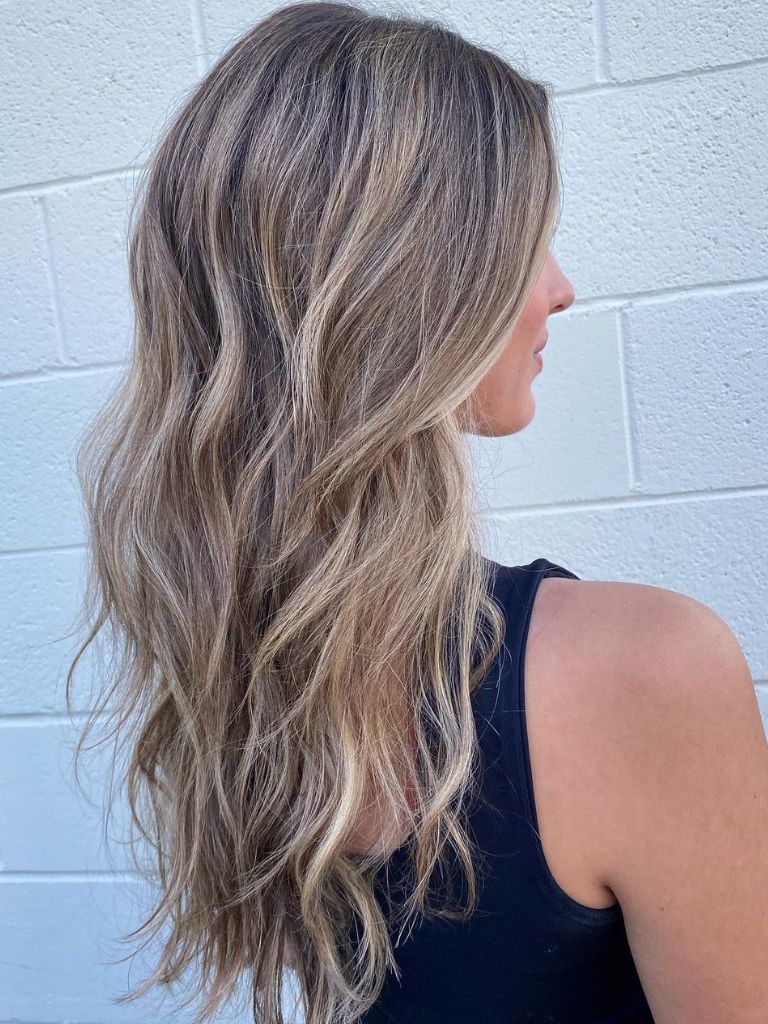 Woman with long wavy blonde dimensional colour hair.