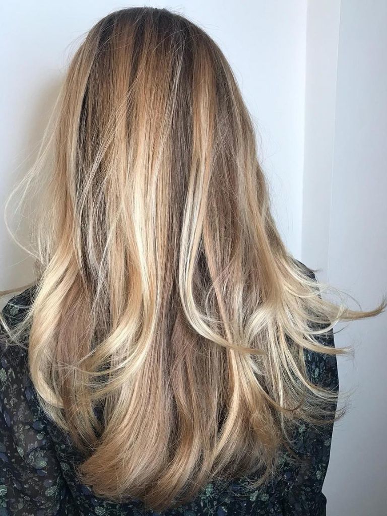 Woman with blonde highlighted hair with wispy layers.