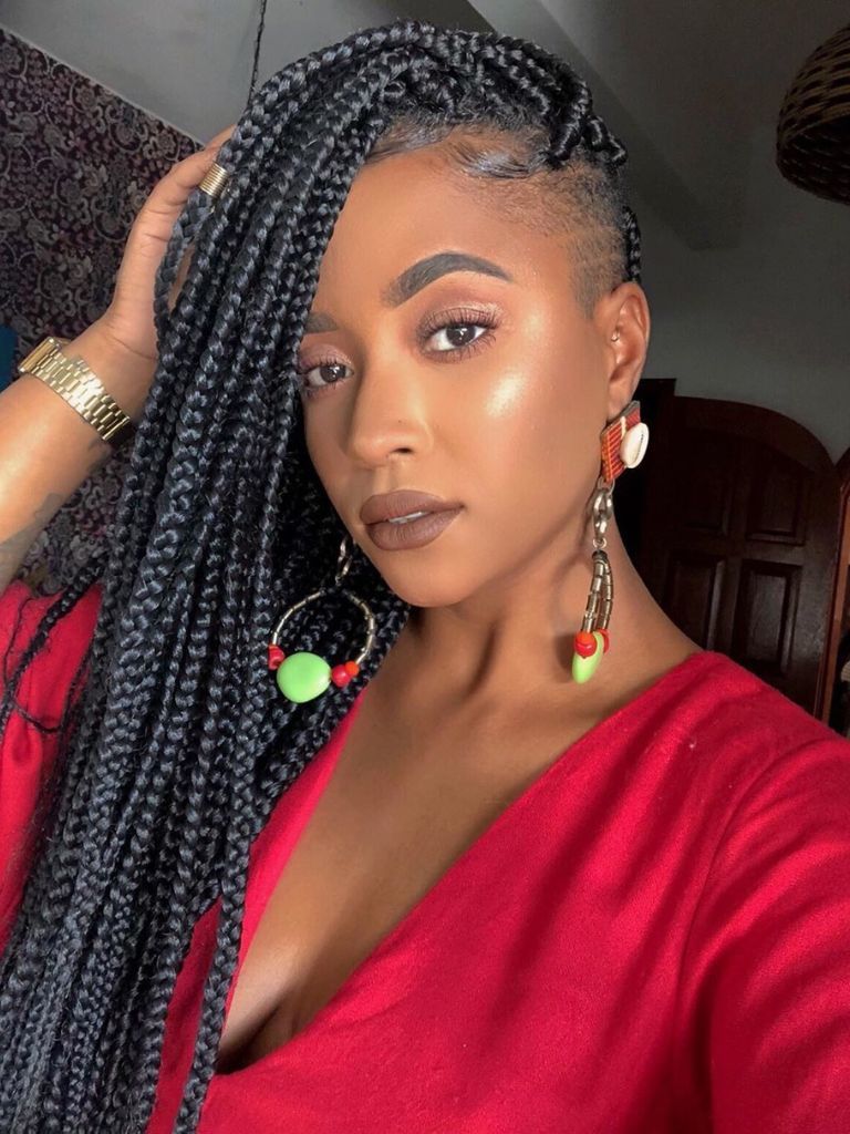 Woman with black side-swept long box braids and a subtle shaved side.
