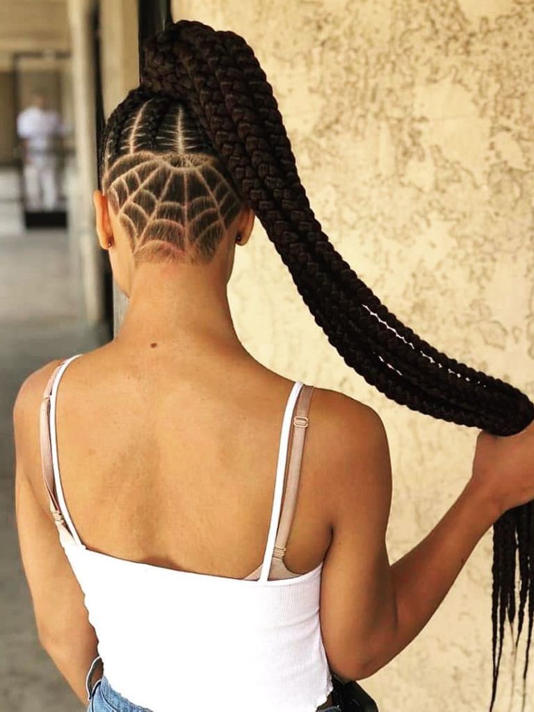 Woman with spider web patterned undercut hairstyle with box braids ponytail.
