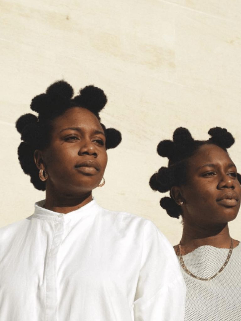 Two women wearing cute Bantu knot puff hairstyles.