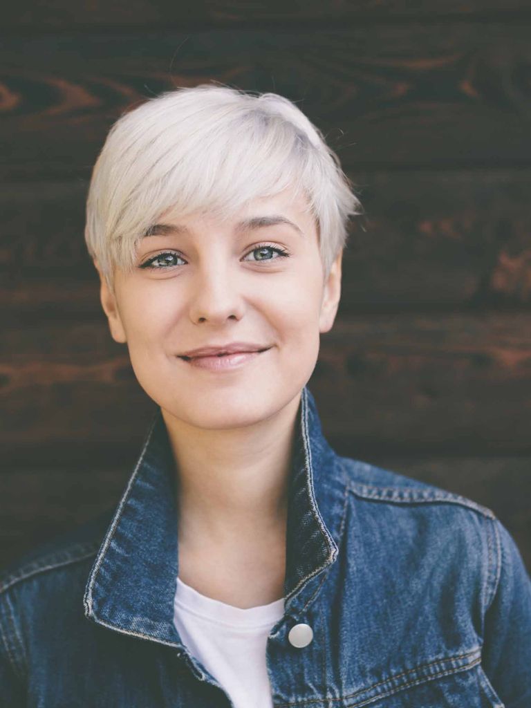 Hairstyles for round faces: blonde woman smiling with pixie haircut.