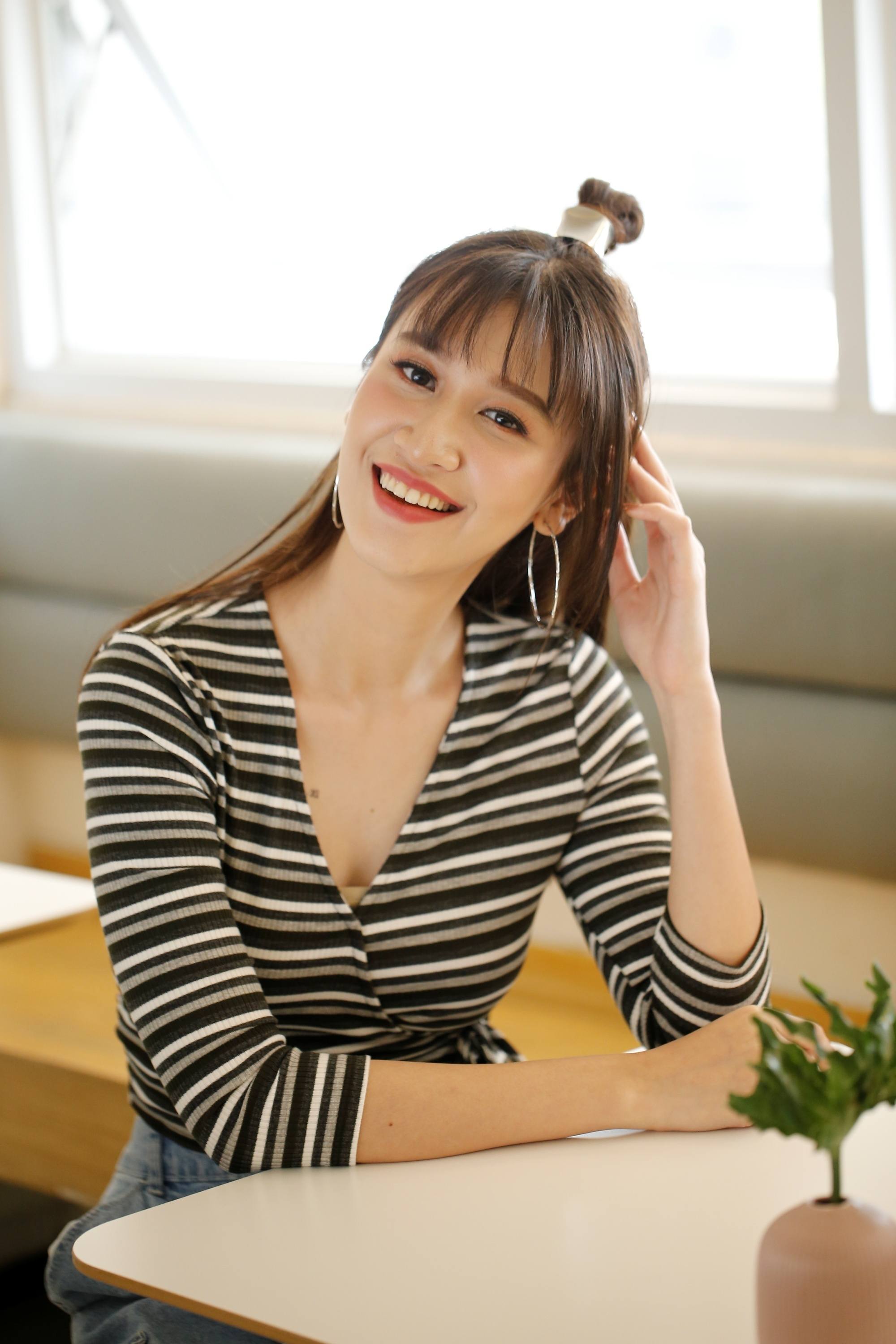 Asian woman with long hair with bangs and a half up top knot