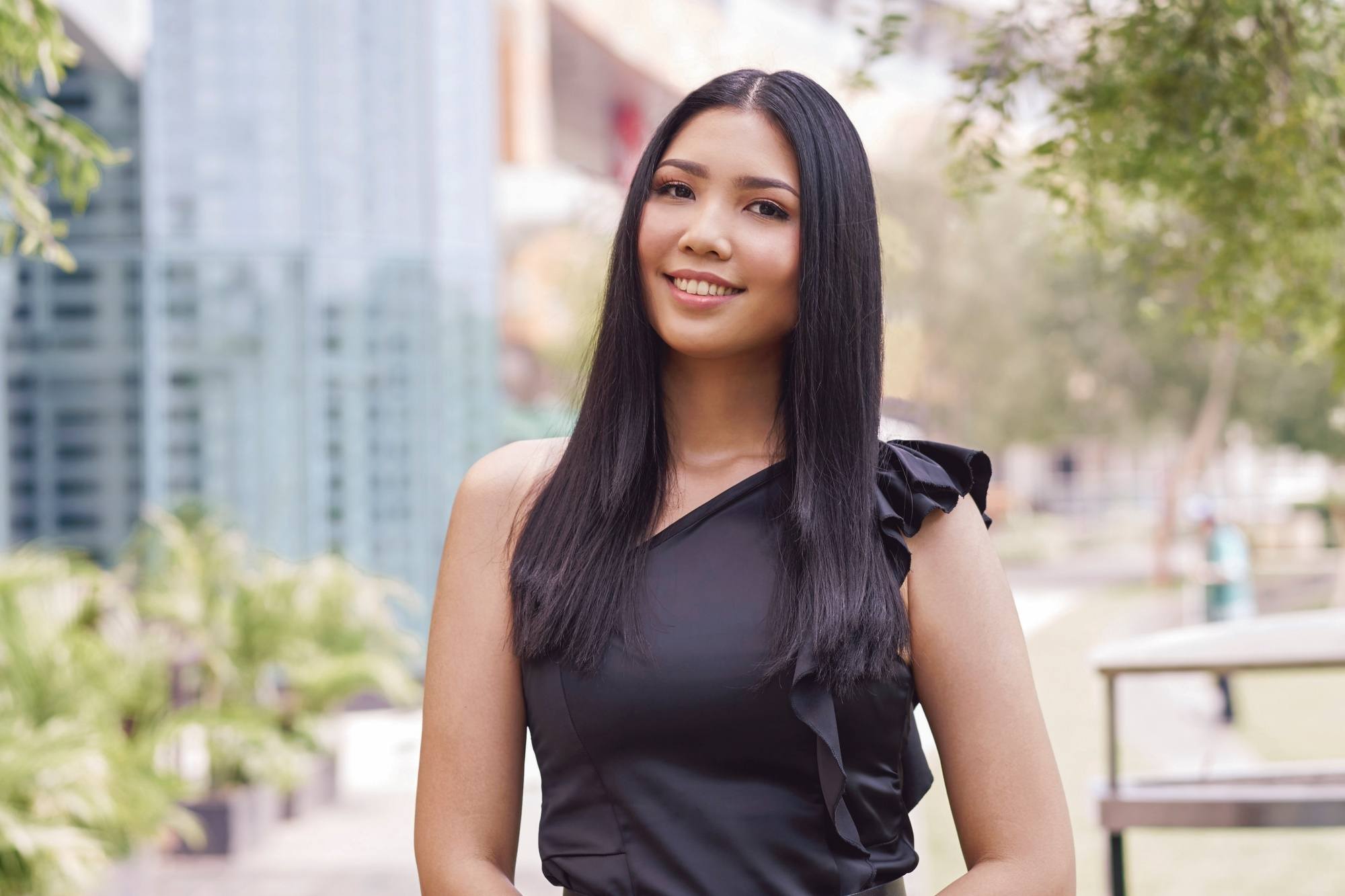 Asian woman with long straight hair standing in a park
