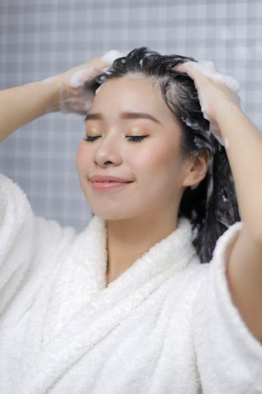 Asian woman putting shampoo on her hair