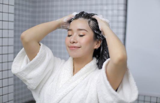 Asian woman putting shampoo on her hair