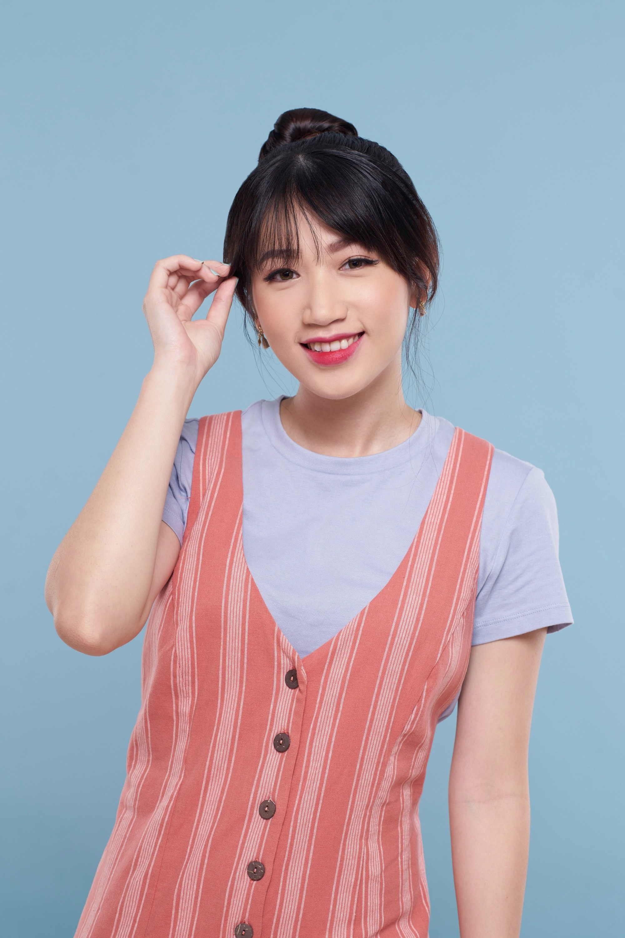 Asian woman with top knot and veiled bangs wearing a jumper dress