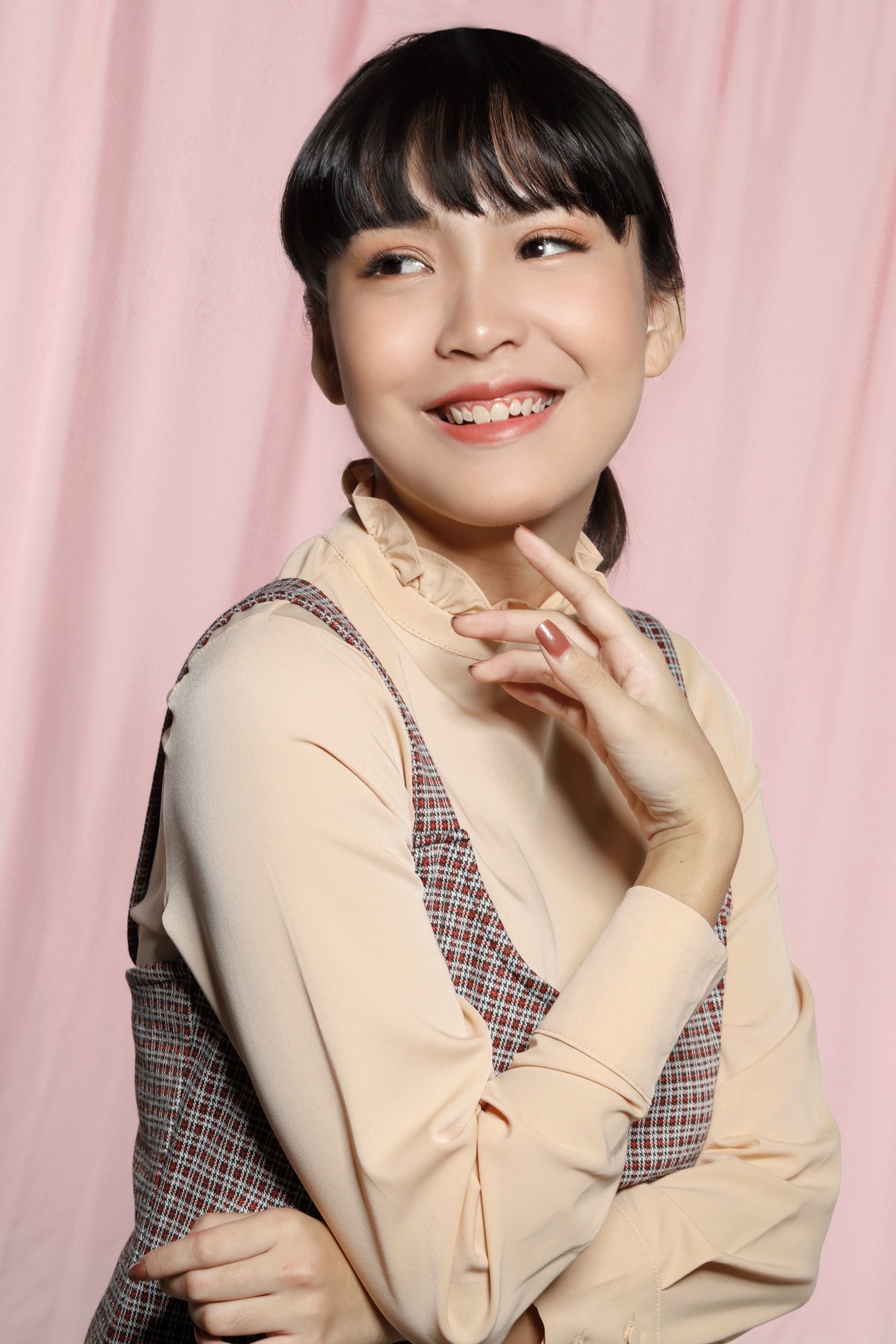 Asian woman with wispy bangs and hair in a ponytail wearing long sleeves