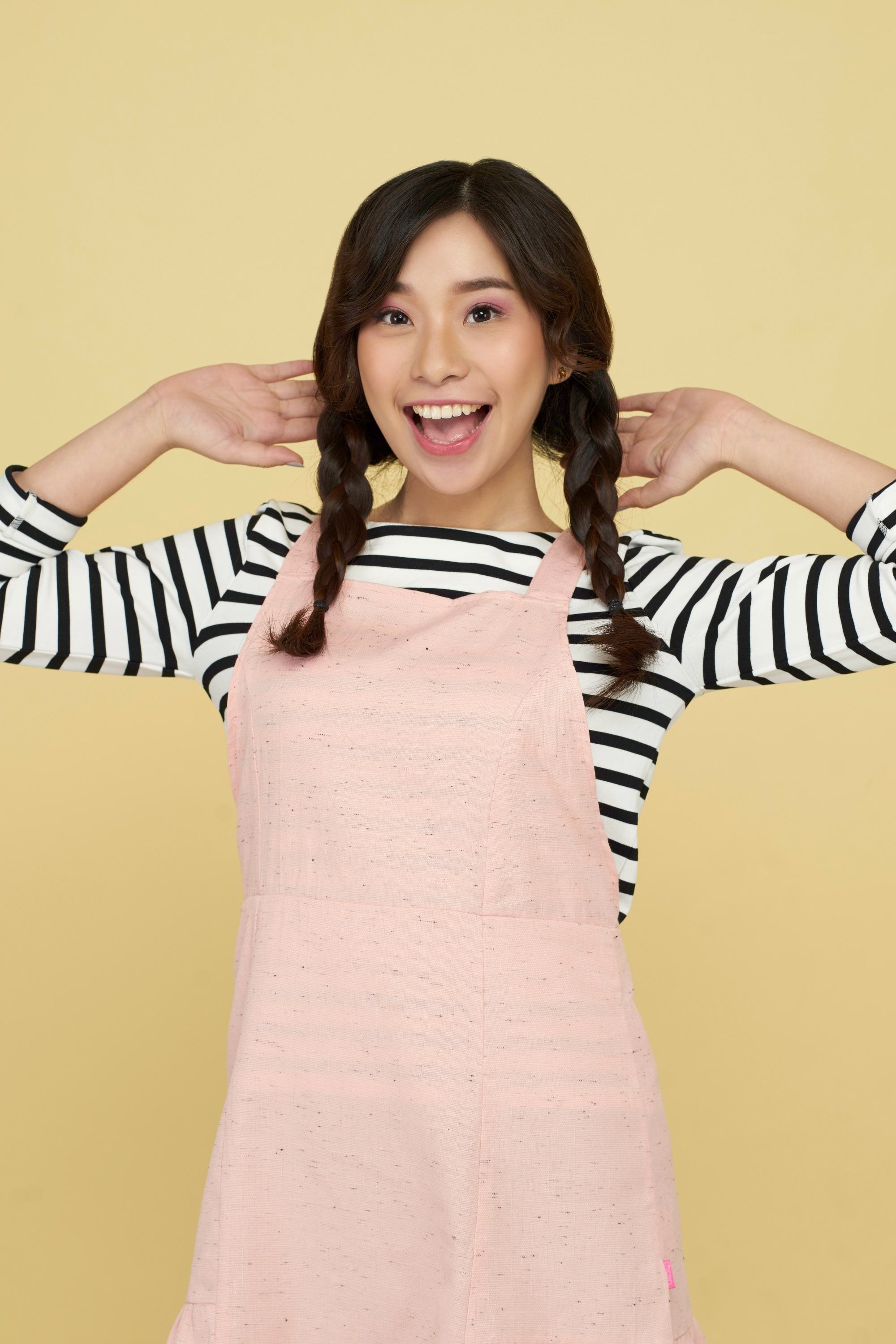 Asian woman with twin braids wearing a pink jumper dress