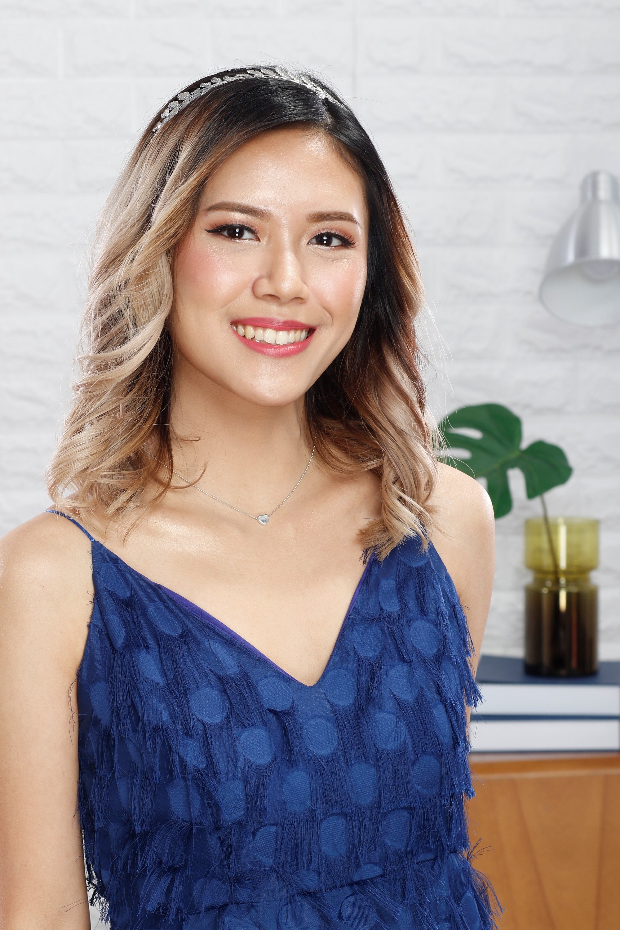Asian woman with blonde hair wearing a blue dress