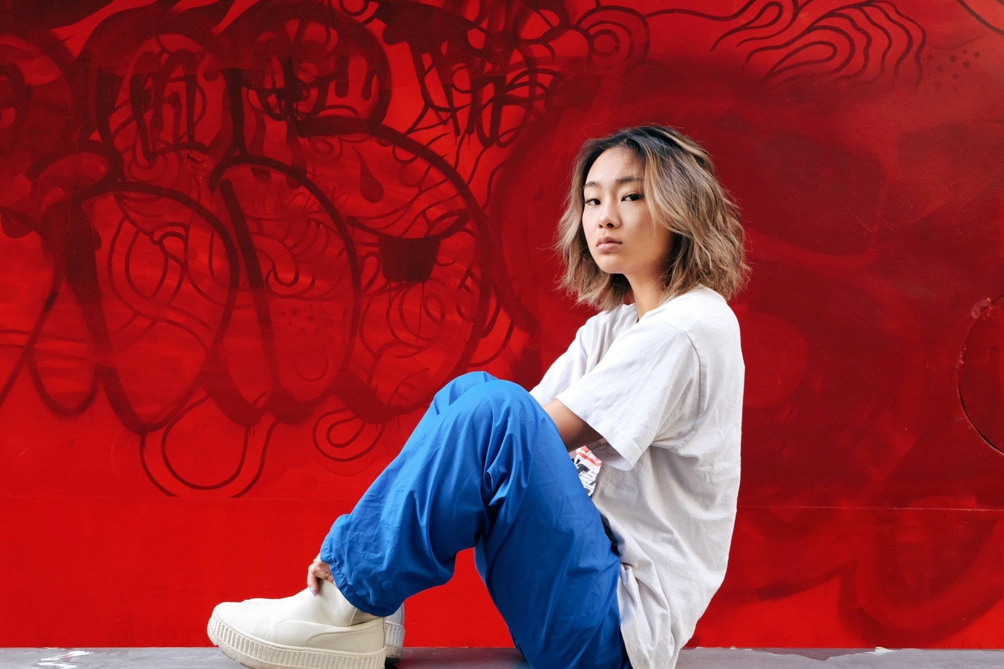 Asian woman with bronde hair sitting on a ledge