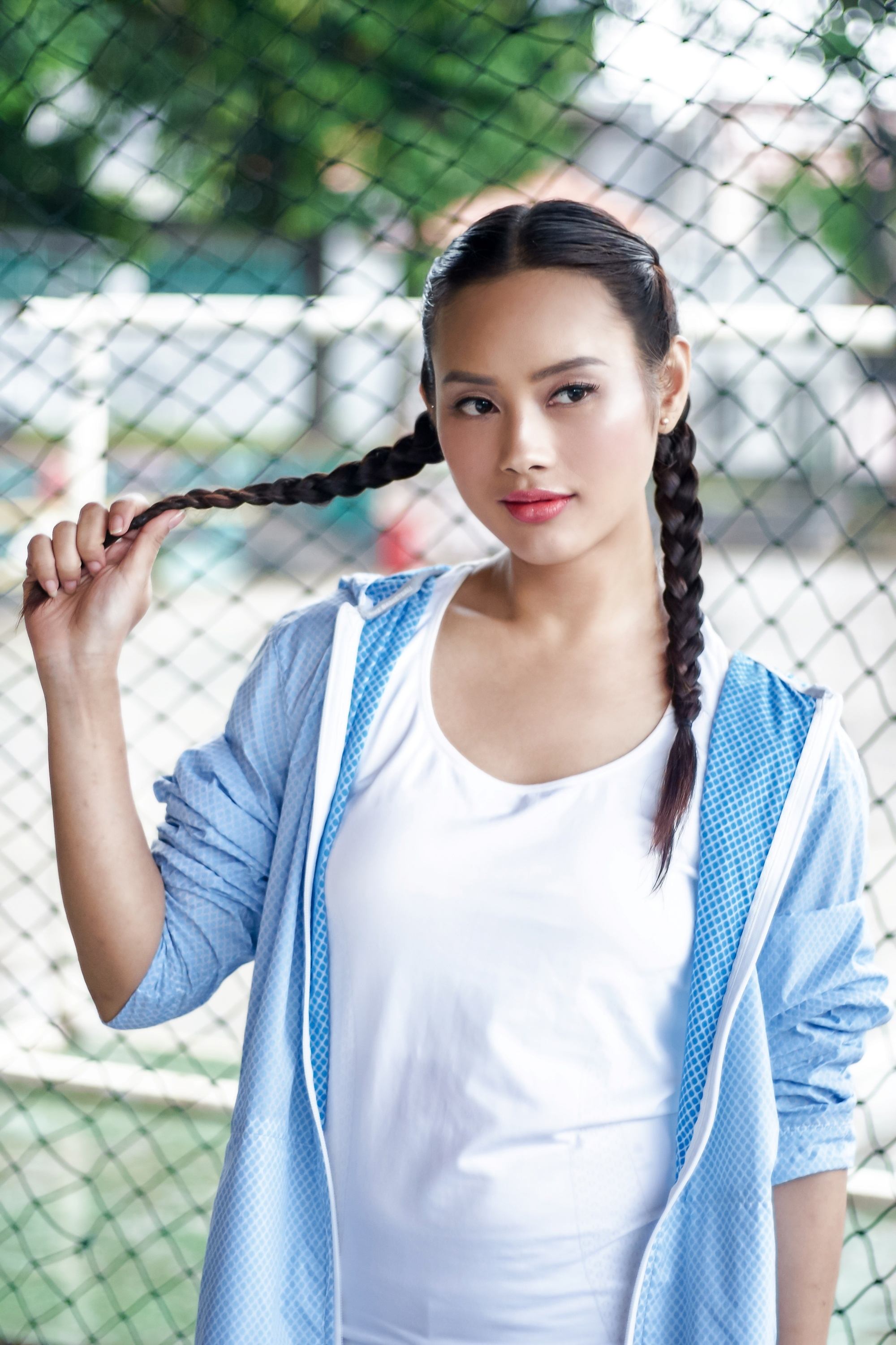 Asian woman with a round face with hair in boxer braid wearing a sporty attire outdoors