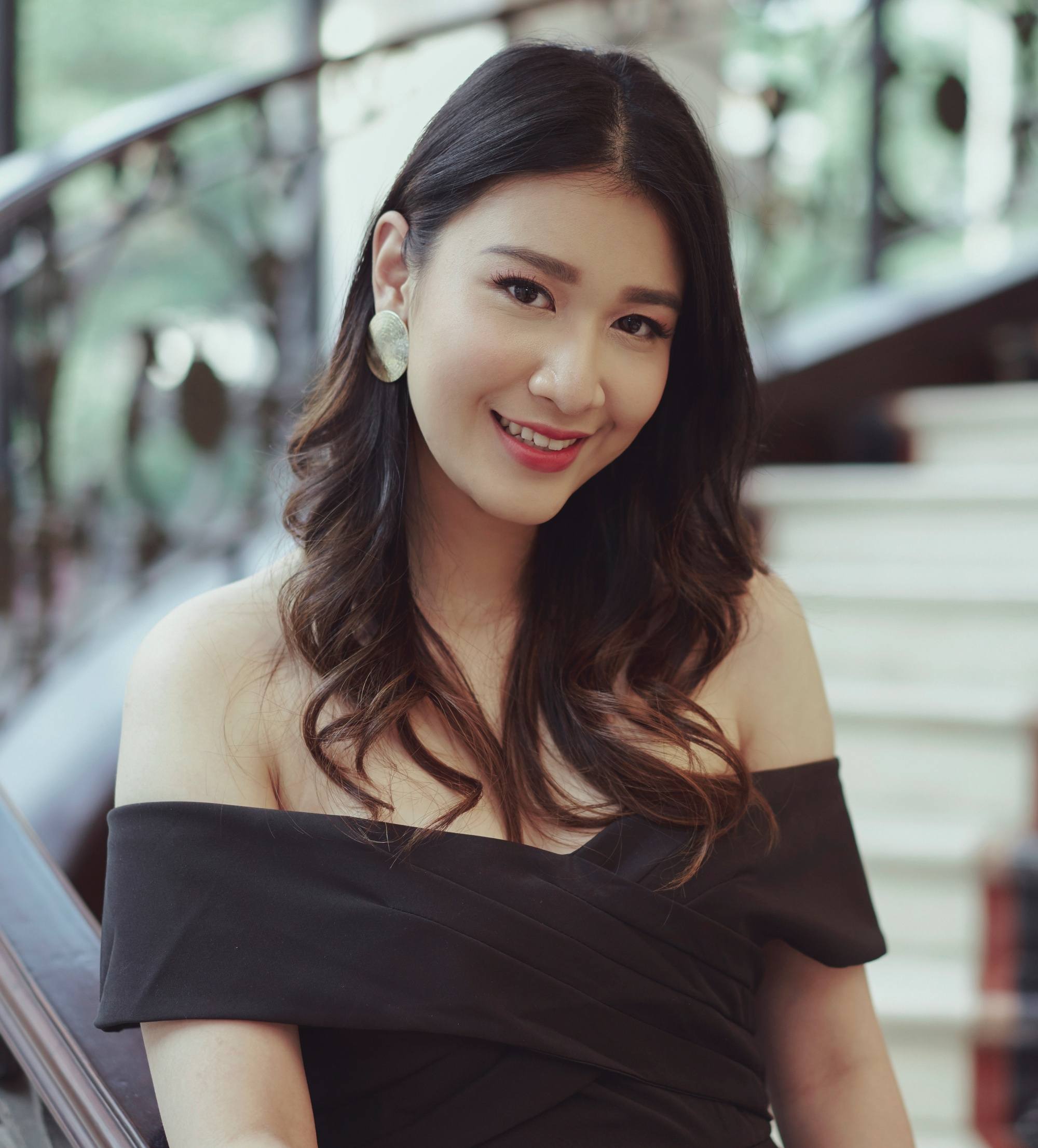 Prom hairstyles for Filipinas: Closeup shot of an Asian woman with long dark wavy hair wearing a black dress