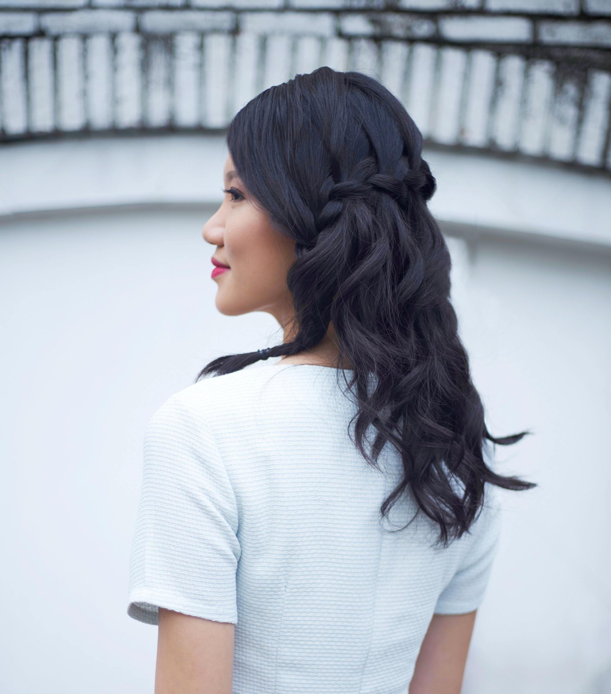 Prom hairstyles for Filipinas: Back shot of an Asian woman with shoulder length black hair in waterfall braid wearing a white dress
