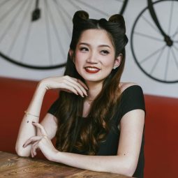 Asian woman with long rockabilly hair in victory rolls sitting in a cafe