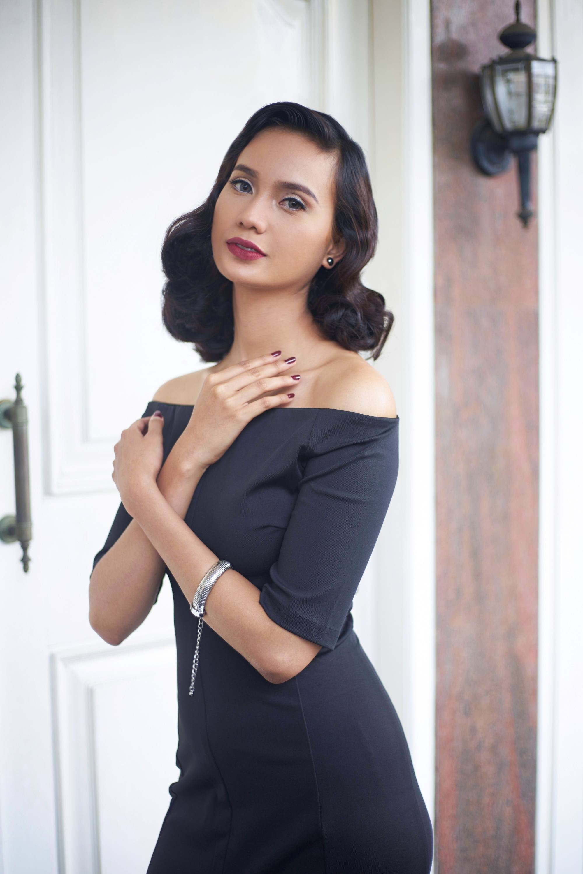 Asian woman with dark shoulder-length curly hair wearing an off-shoulder dress