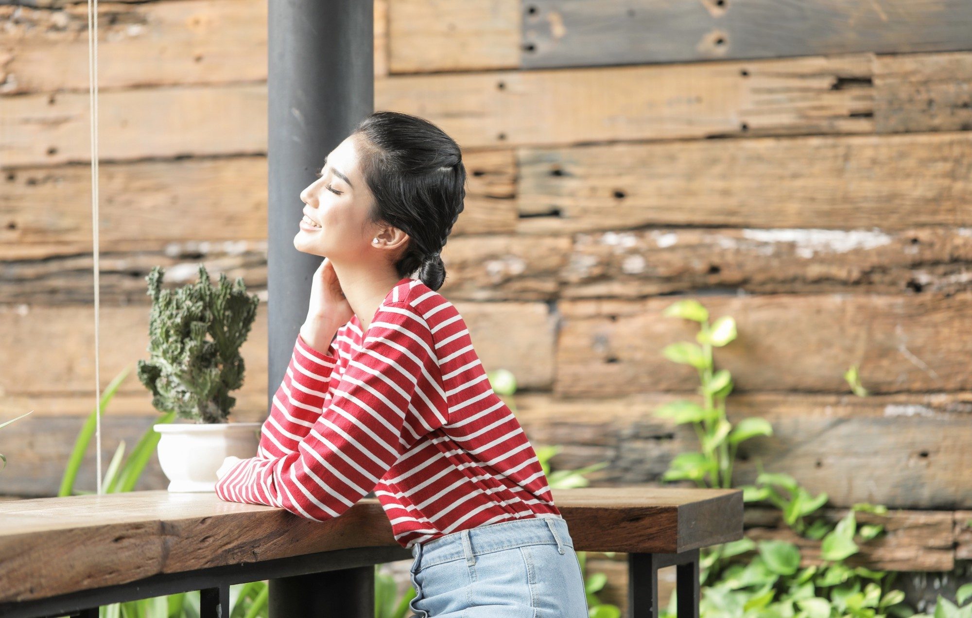 girl wearing a striped top is smiling as she flaunts her pretty low bun hairstyle
