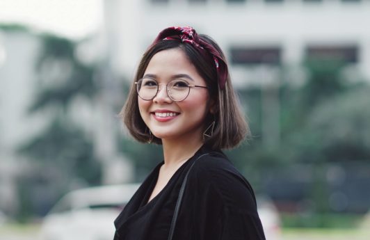 Chin length hairstyles: Asian woman with short dark hair with headband wearing eyeglasses and a black shirt