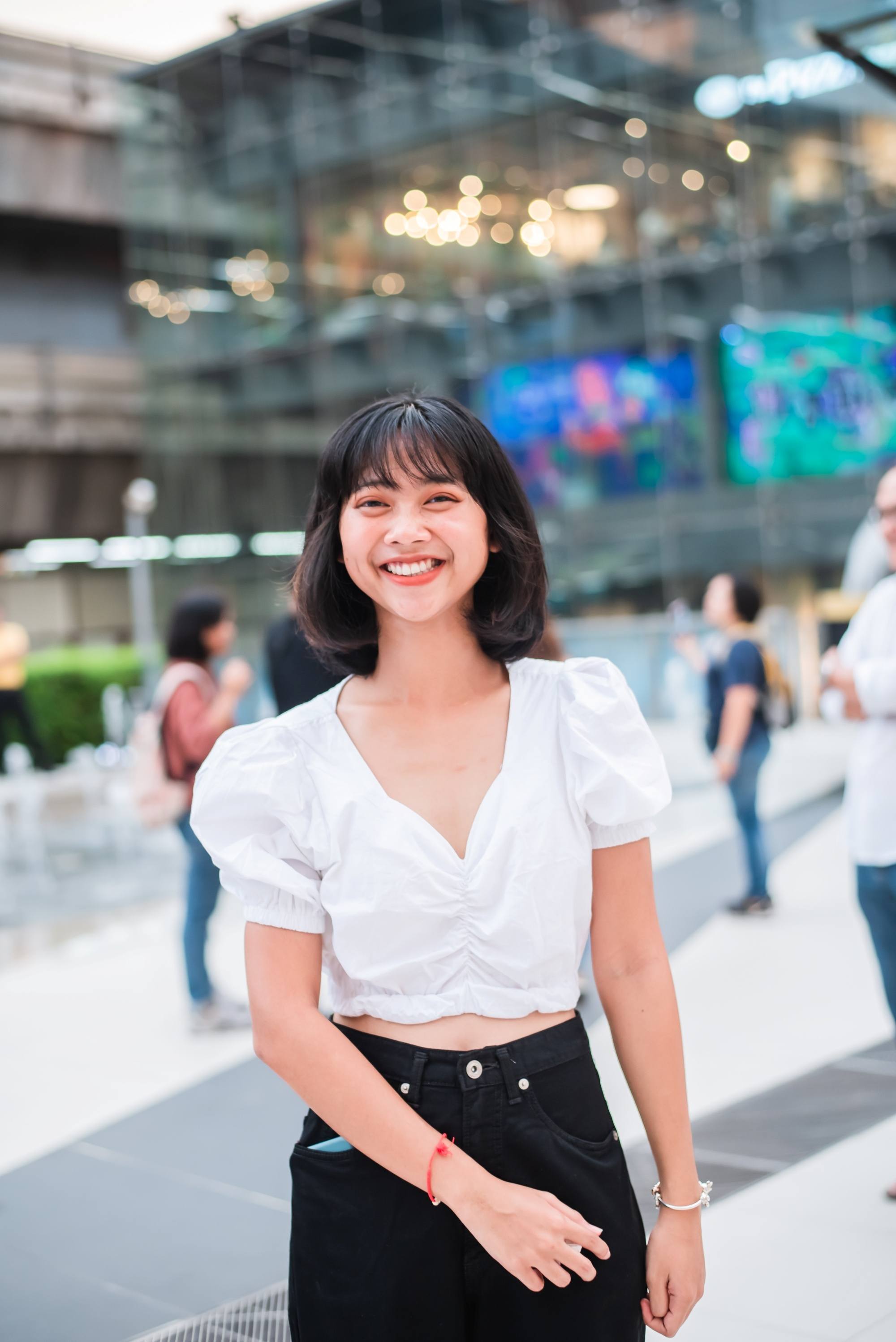 Asian woman with short hair with wispy bangs wearing a white top.