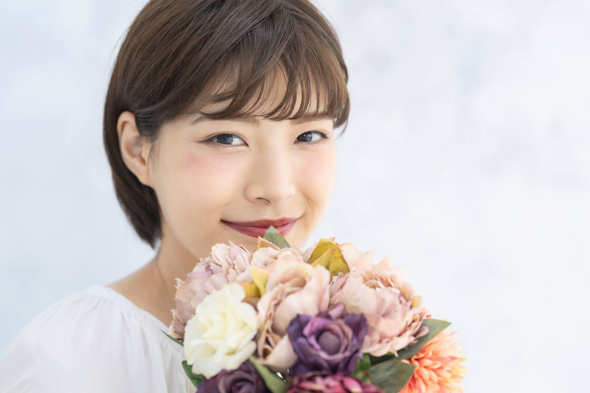 Asian woman with short hair with bangs holding a bouquet of flowers