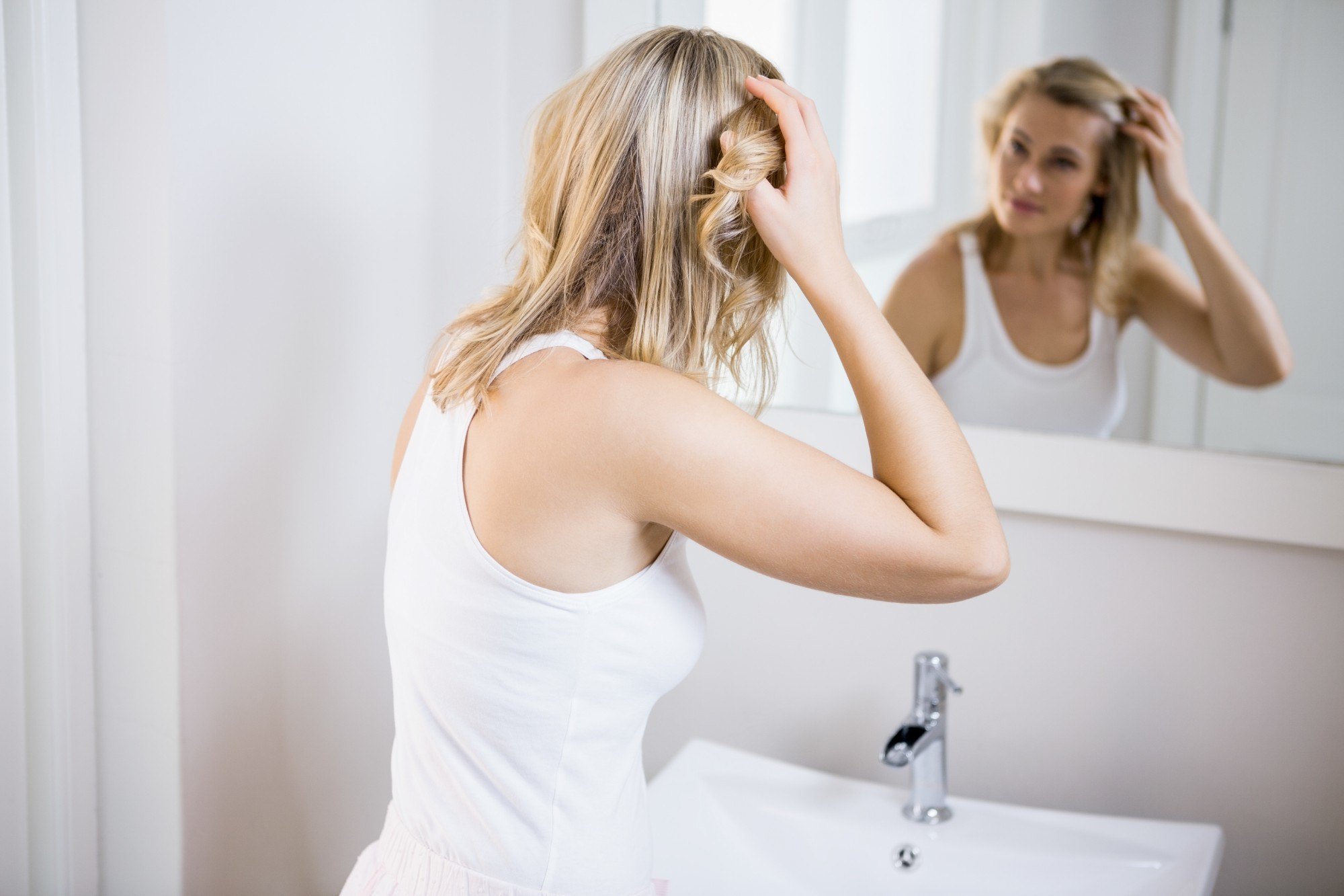 hair fall: girl is looking at the mirror to check her hair